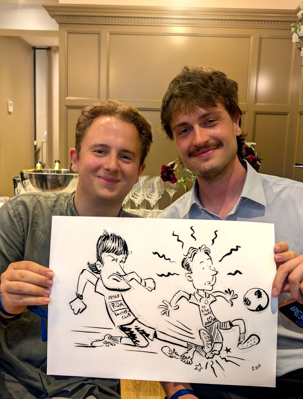 サッカー選手姿の似顔絵を手にした二人の男性